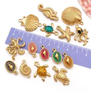 Close-up of various golden stainless steel enamel ocean charms with ruler for scale reference