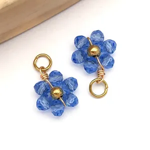 Macro detail of blue crystal flower charms with gold wire wrapping and jump ring