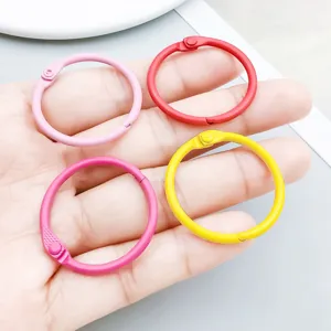 Detailed close-up showing four colorful painted metal loose-leaf binder rings on a palm