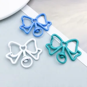 Macro view of three colorful alloy bowknot-shaped keychain charms in blue, white, and teal
