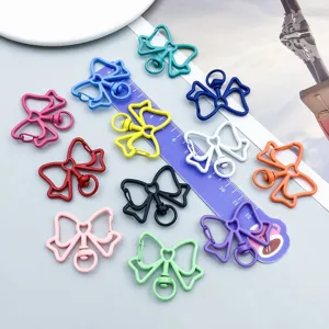 Variety of colorful alloy bow keychain clasps with scale ruler for size reference.