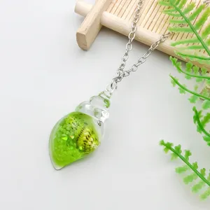 Detail shot of a green ocean conch resin pendant on a silver necklace chain.