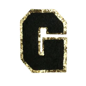 Close-up of black chenille letter G patch with gold glitter border for DIY clothing crafts.
