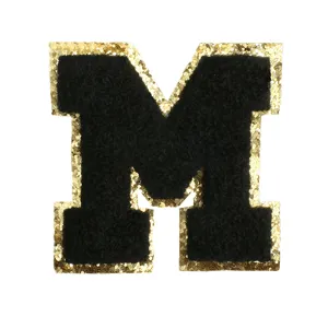 Detailed close-up of letter M patch, black chenille embroidery with gold glitter border.