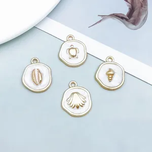 Dettaglio di quattro ciondoli marini in oro e smalto bianco perla per gioielli DIY