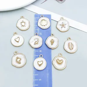 Vista macro dettagliata di ciondoli marini in madreperla bianca con finitura oro e righello