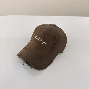 Dettaglio in primo piano del cappellino marrone invecchiato con ricamo bianco e lavaggio vintage.