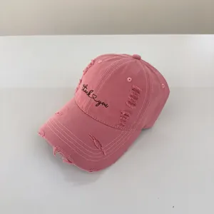 Primo piano di un cappellino da baseball rosa vintage con ricamo grazioso e visiera curva.