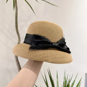 Vue détaillée du chapeau de paille d'été doté d'un élégant nœud en résille noire.