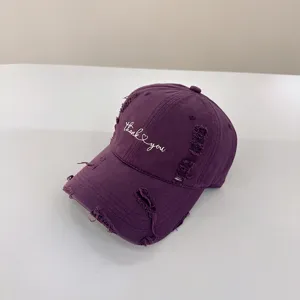 Primo piano di un berretto da baseball viola con testo ricamato e visiera ricurva casuale.