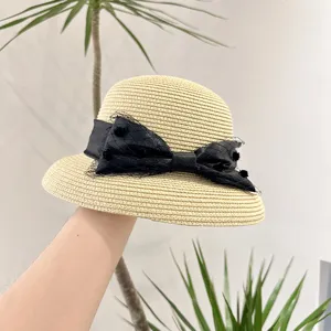 Chapeau de paille beige avec noeud en filet noir, detail elegant de chapeau de soleil d'ete.