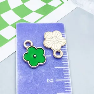 Vista detallada de dijes de flores de esmalte verde con escala de medidas
