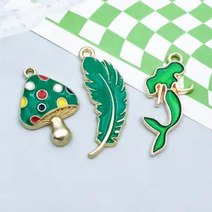 Detalle de dijes de aleación esmaltada verde con forma de hongo, hoja y sirena