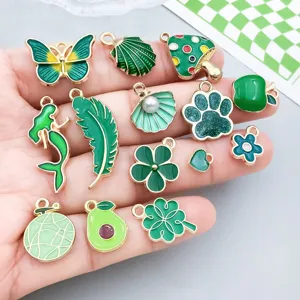 Dijes variados de esmalte verde con formas de mariposa y trébol para bisutería artesanal.