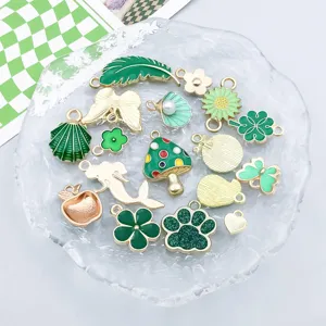 Primer plano de dijes de esmalte verde mezclados en varias formas en un plato.