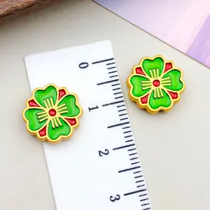 Close-up of green and red enamel cherry blossom clover beads with ruler for scale.