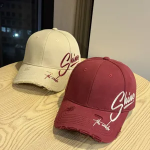 Detailansicht von Distressed-Baseballcaps in Beige und Bordeaux mit schickem Stick.