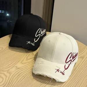 Detailansicht von distressed Baseballcaps in Schwarz und Weiß mit bestickten Schriftzügen.