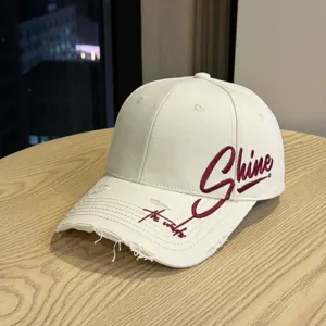 Lässige cremefarbene Baseballkappe mit Destroyed-Effekt und weinroter Stickerei für Damen.