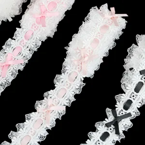 Dettaglio di pizzo bianco largo 4 cm con fiocchi rosa per cucito e decorazioni fai da te.