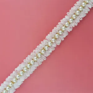 Close-up detail of white ruffled lace trim with center faux pearls and gold links for DIY crafts.