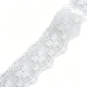 Primo piano di bordo in pizzo di cotone bianco con delicato ricamo floreale e tessuto in rete.