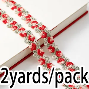 Red and green floral lace ribbon trim close-up shot, delicate embroidery sewing accessory.