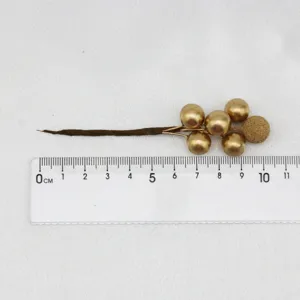 Gold artificial berry stem detail view, Christmas decoration prop branch, close-up showcase.