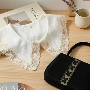 Close-up detail of a white lace detachable fake collar with delicate embroidery and floral trim.