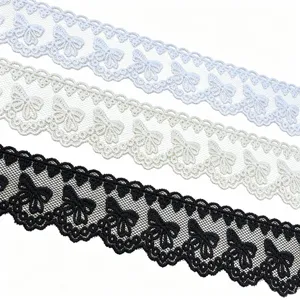 Close-up detail of embroidered butterfly mesh lace trim, featuring white, beige, and black colors.