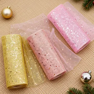 Detailed close-up of glitter tulle fabric rolls in gold and pink for holiday craft decor.