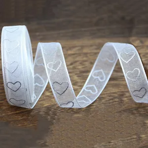 Detail shot of white sheer organza ribbon with silver hearts, perfect for wedding gift wrapping.