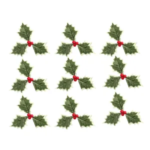 Vue détaillée de feuilles de houx de Noël artificielles et baies rouges pour déco de fête.