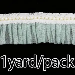 Detail view of green ruffled mesh lace trim with pearls, ideal for wedding dress sewing.