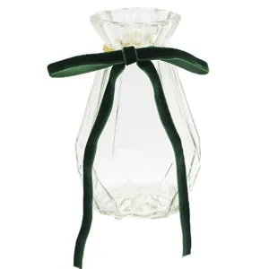 Transparent glass faceted vase with elegant dark green velvet bow detail close-up view.