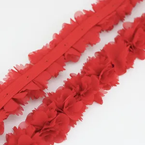 Dettaglio del bordo in pizzo floreale di chiffon rosso per cucito e decorazioni fai da te.