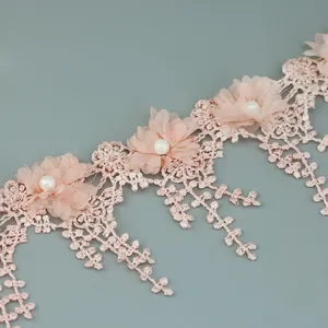 Close up of pink petal lace trim with pearls and delicate flower details, ideal for crafts.