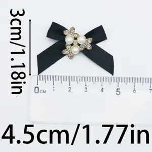 Gros plan d'un noeud papillon en tissu noir avec perle et strass, taille 3x4.5 cm.
