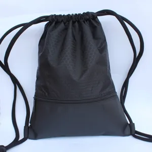 Detail view of simple black drawstring backpack, hexagonal pattern upper part, front zipper pocket.