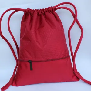 Detailed view of the red nylon drawstring backpack featuring a front zipper pocket and honeycomb top.