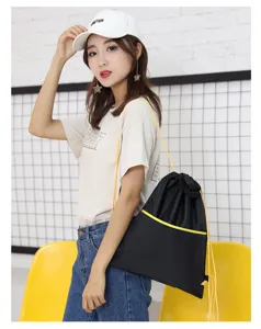 Black oxford cloth drawstring backpack, portable travel bag with yellow trim and spacious interior.