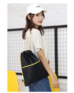 Black oxford cloth drawstring backpack detail showing yellow cord and front pocket design.