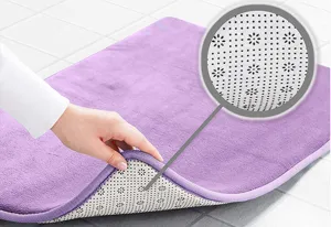 Gros plan détaillé du tapis de bain violet montrant les détails du dos antidérapant.