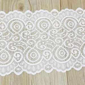 Detail shot of white stretch lace fabric trim, delicate hollow floral pattern for DIY sewing crafts.