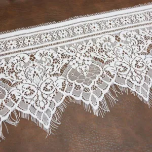 Gros plan de tissu de bordure en dentelle blanche avec motifs floraux pour couture et loisirs.