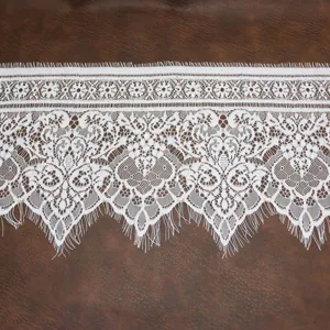 Gros plan détaillé d'une bordure en dentelle blanche avec motif floral et franges.