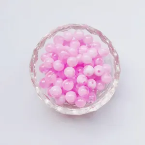 Close-up detail of glossy pink acrylic round beads in a crystal bowl, ideal for DIY jewelry crafting.