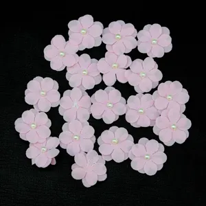 Detail view of 2.5cm pink fabric 5-petal flower appliqués with pearl center for DIY crafts.