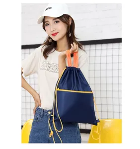 Close-up detail of a dark blue nylon drawstring backpack with bright yellow accents and orange handles.