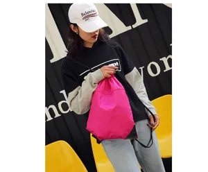 Lightweight nylon drawstring backpack in bright pink with shoulder straps and front pocket.